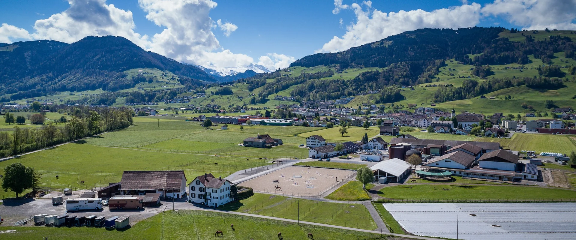 Luftaufnahme der Reitanlage der Züger Pferdesport AG in Galgenen vor Bergkulisse
